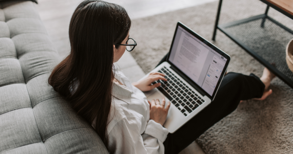 Γυναίκα εργάζεται από το σπίτι σε laptop, καθισμένη σε καναπέ